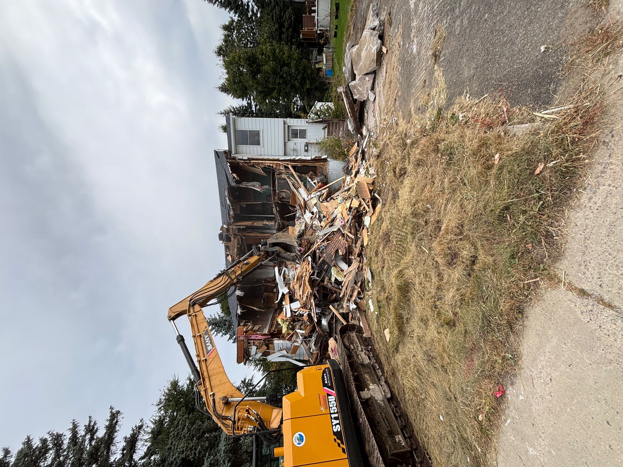 Démolition de maison résidentielle avec pelle mécanique et débris de construction à Québec